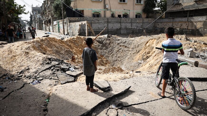 Children stand near a crater caused by Israeli bombardment in a street in Rafah in the southern Gaza Strip