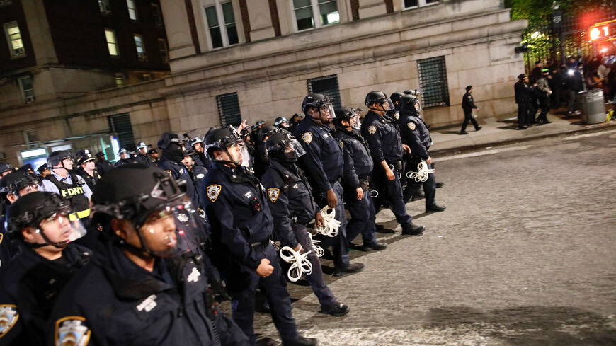 NYPD officers in riot gear march onto Columbia University campus, where pro-Palestinian students are barricaded inside a building and have set up an encampment, in New York City on April 30, 2024. Columbia University normally teems with students, but a "Free Palestine" banner now hangs from a building where young protesters have barricaded themselves and the few wandering through campus generally appear tense. Students here were among the first to embrace the pro-Palestinian campus encampment movement, whic