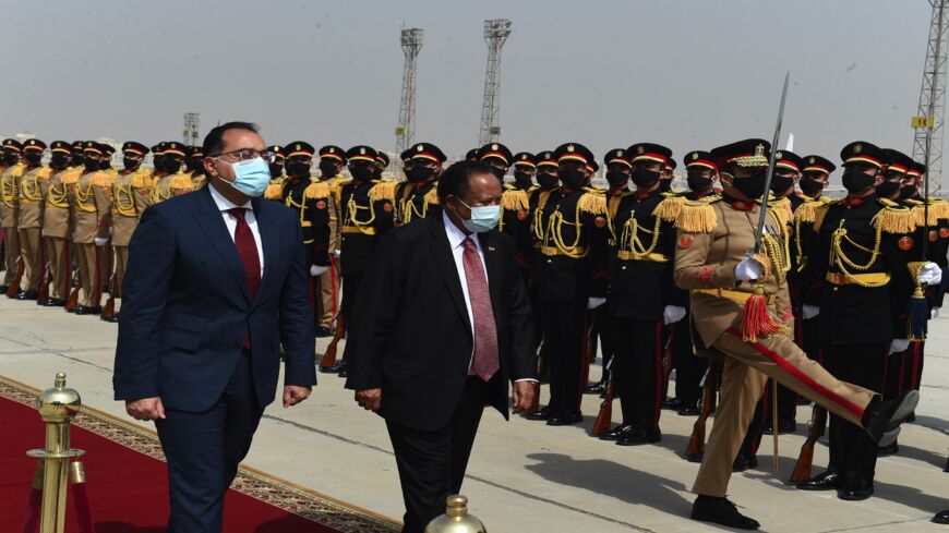 Egyptian Prime Minister Mostafa Madbouly (L) welcomes his Sudanese counterpart, Abdalla Hamdok, upon his arrival in the Egyptian capital Cairo, on March 11, 2021. - Sudan, Egypt and Ethiopia have been locked for almost a decade in inconclusive talks over the filling and operation of the Grand Ethiopian Renaissance Dam (GERD) on the Blue Nile, which broke ground in 2011.