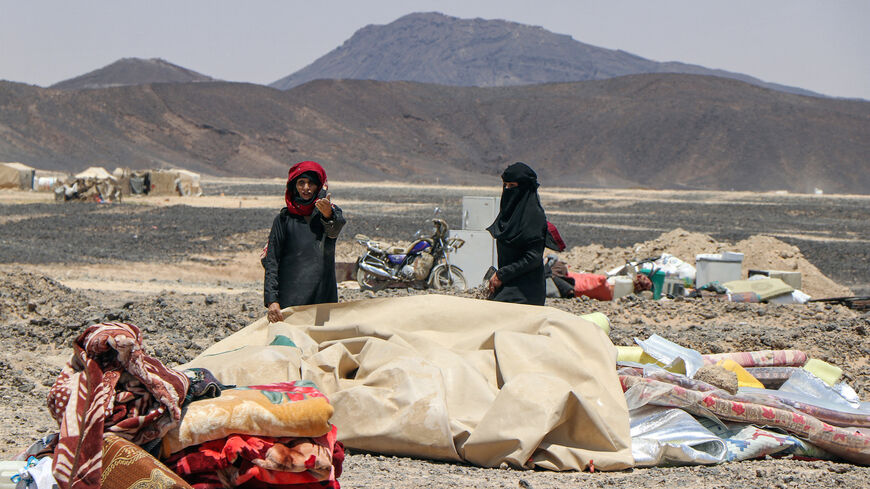 Women wait next to belongings at a camp for the internally displaced about 10 kilometres on the outskirts of Yemen's northeastern city of Marib on March 28, 2021, as residents of the camp prepare to flee due to its proximity with battles between forces of the Houthi-rebels and the Saudi-backed government troops. 