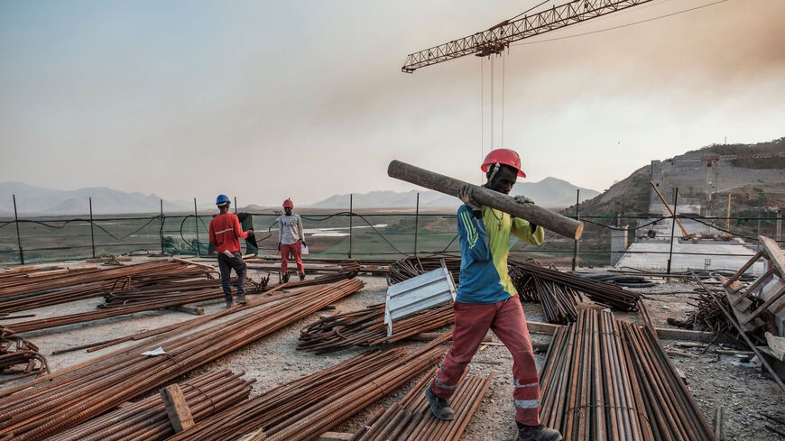 A worker walks with a piece of wood on his shoulder at the Grand Ethiopian Renaissance Dam (GERD), near Guba in Ethiopia, on Dec. 26, 2019. 
