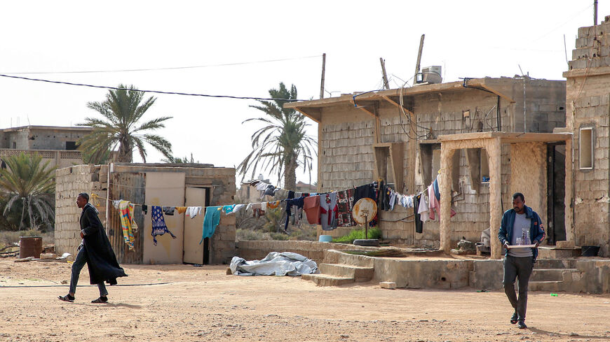 A man walks near a laundry clothing line hanging in the open by a building in the city of Tawergha, some 200 kilometres (125 miles) east of Libya's capital close to the port city of Misrata, on Dec. 12, 2020.