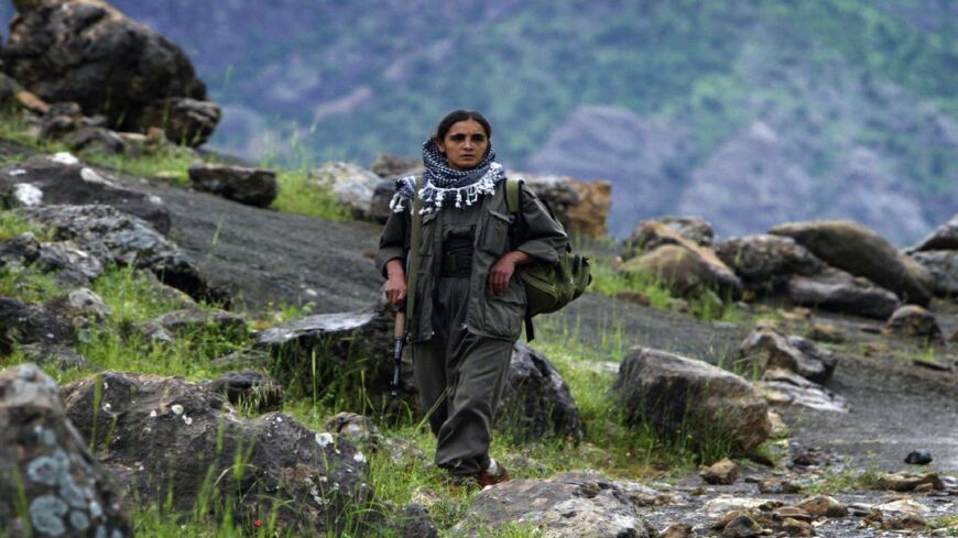 A Kurdish female peshmerga fighter carries her weapon while walking in the foothills of the Qandil Mountains located along the Iraq-Iran border, May 5, 2006.