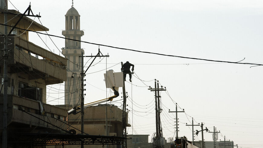 An Iraqi municipal worker fixes the cables of an overhead power line in al-Zahraa neighborhood in Mosul, during an ongoing military operation against the Islamic State, Iraq, Jan. 11, 2017.
