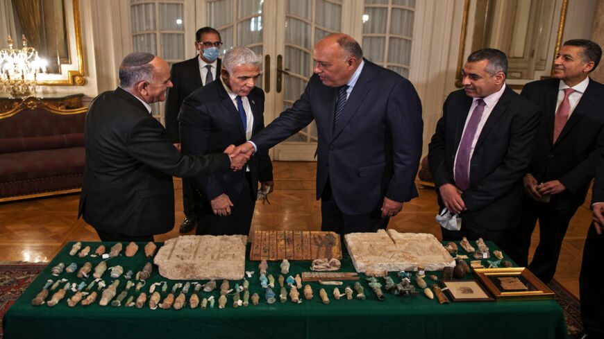 Egypt's Foreign Minister Sameh Shoukry (C) shakes hands with the director of the Israel Antiquities, Authority Eli Escozido (L).