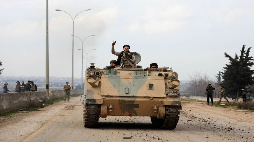 Members of the Syrian National Army, an alliance of Turkey-backed rebel groups, ride in an armored personnel carrier in the town of Sarmin as they take part in a military offensive on the village of Nayrab following an artillery barrage fired by Turkish forces, near Idlib, Syria, Feb. 24, 2020.