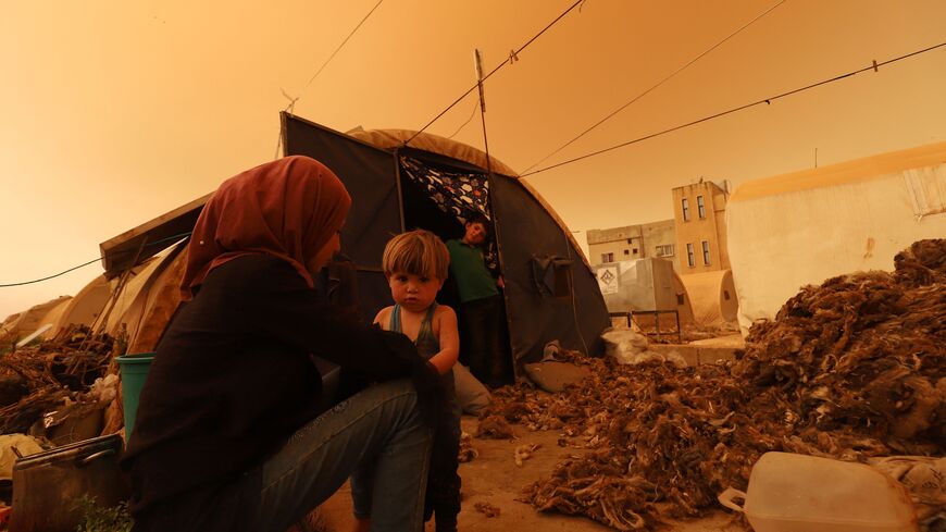 A displaced family sits next to their tent during a dust storm over the town of Zardana in the countryside of the northwestern Idlib province, Syria, June 2, 2022.