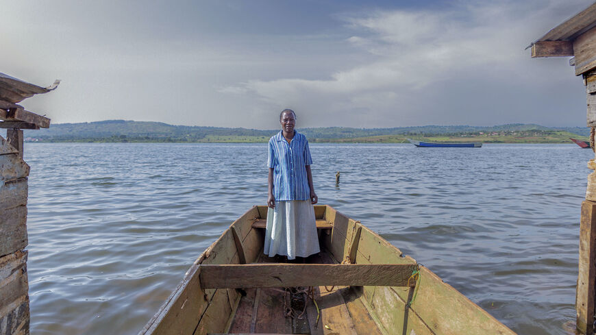 Agnes Naigaga, 53, stands on Lake Victoria in a boat, at the spot where her clinic once stood, Aug. 27, 2021. 