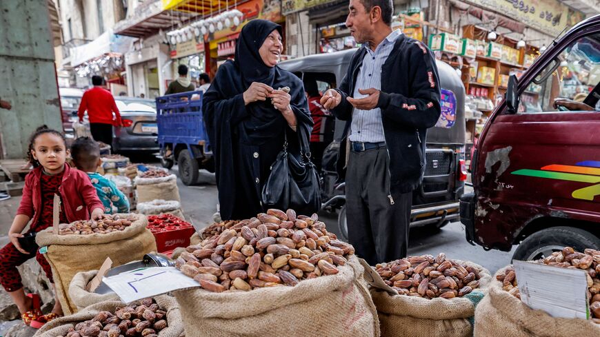 In this picture taken on March 22, 2023, a woman speaks with a merchant as she shops for dates at the traditional Rod el-Farag market in northern Cairo during the Muslim holy fasting month of Ramadan. - Muslims follow the tradition set by the prophet Mohammed whom believers say used to break his fast by eating dates and drinking goat's milk during the holy month. The dawn-to-dusk fast is conceived as a spiritual struggle against the seduction of earthly pleasures, but the evening iftar festive meals traditi