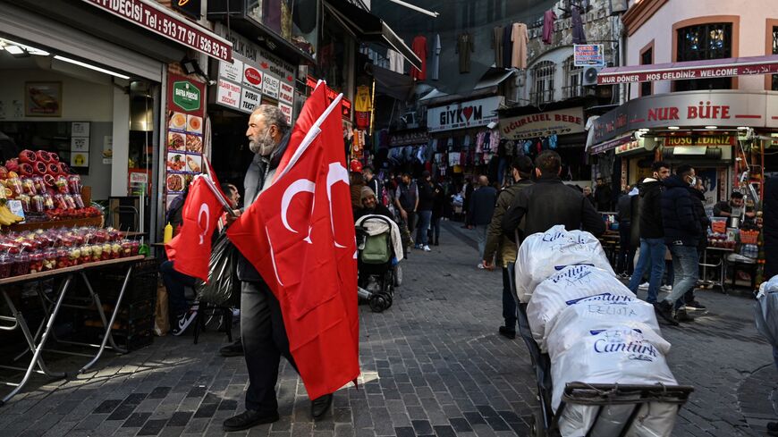 A seller of Turkish national flags walks at Mahmutpasa district, one of Istanbul's biggest textile shopping centre, near Grand Bazaar, on Dec. 2, 2021.