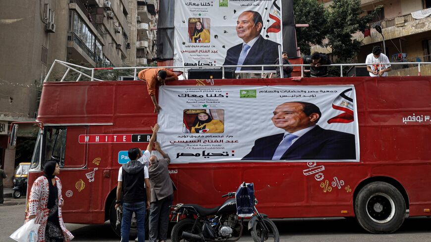 Supporters hang a campaign banner of Egypt's President Abdel Fattah al-Sisi at a bus on a street in Cairo on December 7, 2023, ahead of the country's presidential election.