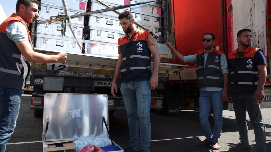 Volunteers unload a truck as a convoy carrying humanitarian aid arrives in Syria after crossing the Bab al-Hawa border crossing with Turkey, on Sept. 19, 2023. 
