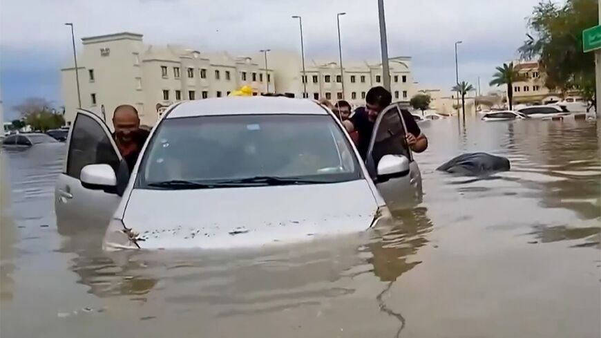 Residents push a waterlogged car along a flooded street in the desert city of Dubai after torrential rains paralysed the Gulf financial and leisure hub
