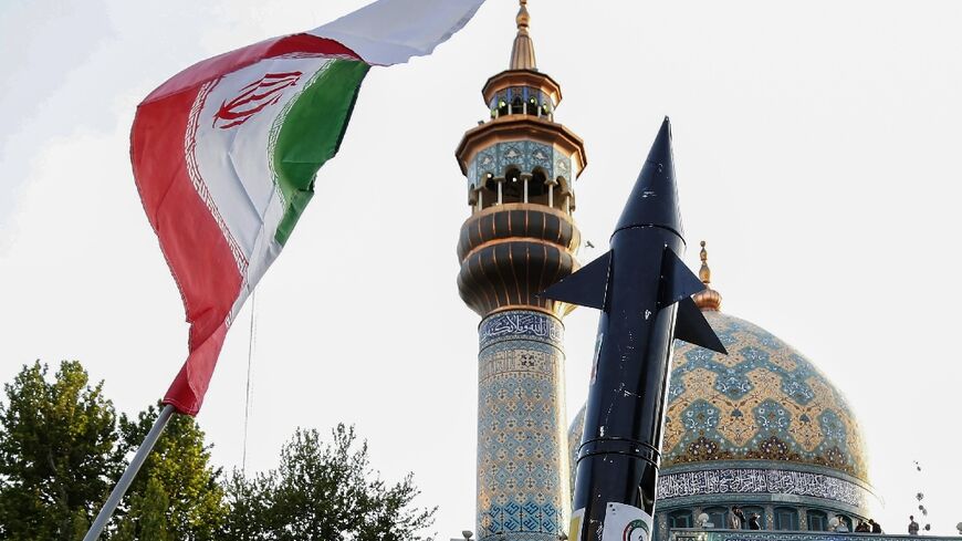 Iranians lift up a flag and the mock up of a missile during a celebration following Iran's missiles and drones attack on Israel, on April 15 2024, at Palestine square in central Tehran