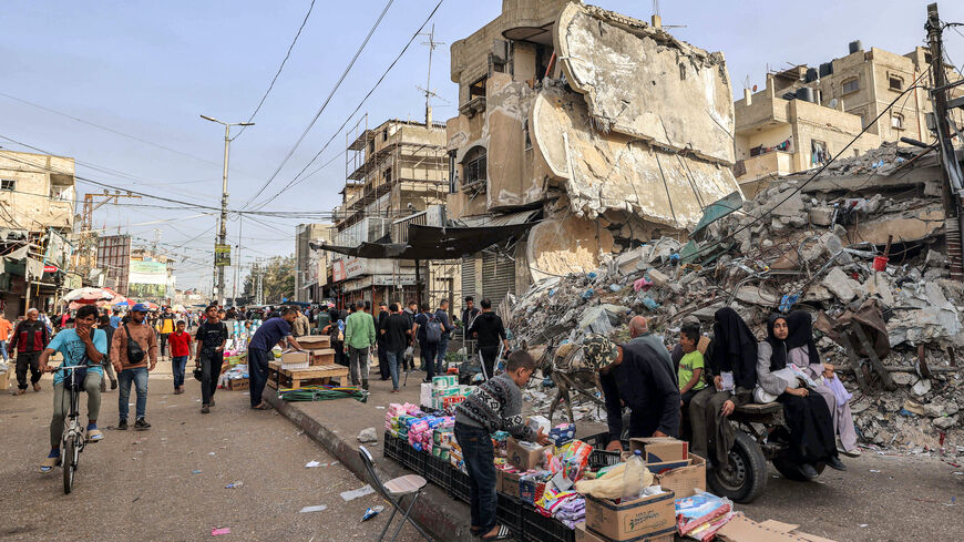 A boy helps a vendor arrange his merchandise as he sets up before the rubble of a collapsed building in Rafah in the southern Gaza Strip on April 23, 2024 amid the ongoing conflict in the Palestinian territory between Israel and the militant group Hamas. 