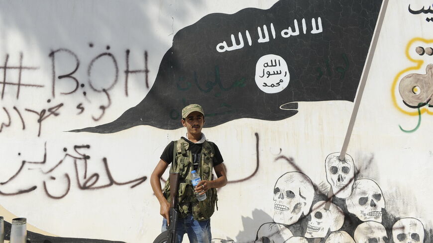 JARABLUS, SYRIA - AUGUST 31: A member of the Turkish-backed Free Syrian Army (FSA) stand guarded in front of a ISIS flag in the border town of Jarablus, August 31, 2016, Syria. Turkish troops and Turkey-backed rebels have been fighting Kurdish-led forces and IS since Turkey's incursion into Syria on Aug. 24. with the swift capture of Jarablus, a town a few km inside Syria that was held by Islamic State.(Photo by Defne Karadeniz/Getty Images)