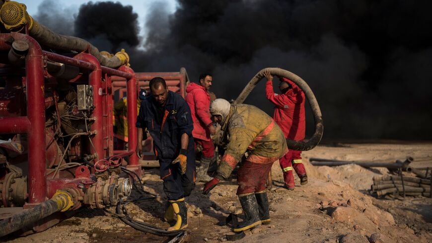 Workers tasked with putting out the fire in an oil well, set ablaze by retreating Islamic State (IS) jihadists, assemble a water pipeline in the town of Qayyarah.
