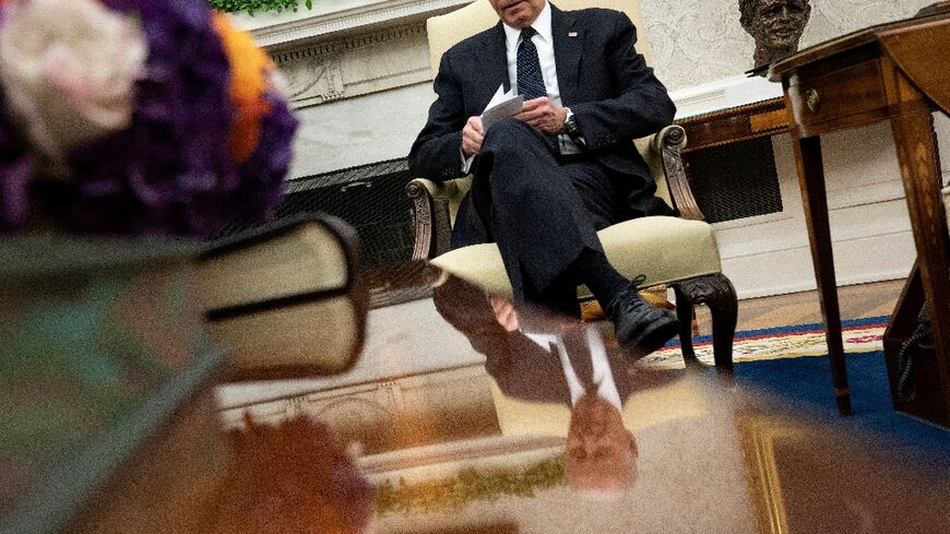 US President Joe Biden looks at note cards as he meets with Romanian President Klaus Iohannis in the Oval Office of the White House in Washington, DC, on May 7, 2024.
