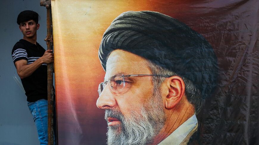 Men hang a huge portrait of Iran's late president Ebrahim Raisi outside the Iranian embassy in Baghdad 