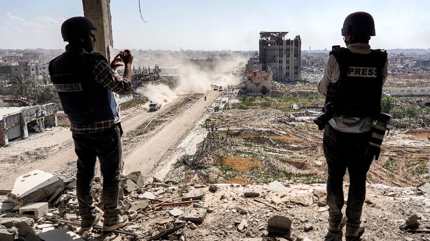 Journalists film from atop a damaged building facing the ravaged Al-Salam hospital in Khan Yunis in Gaza in April 2024