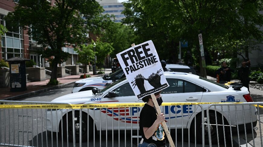 A demonstrator holds a sign as a police vehicle and barricades block a road after officers cleared a pro-Palestinian student protest encampment at George Washington University on May 8, 2024