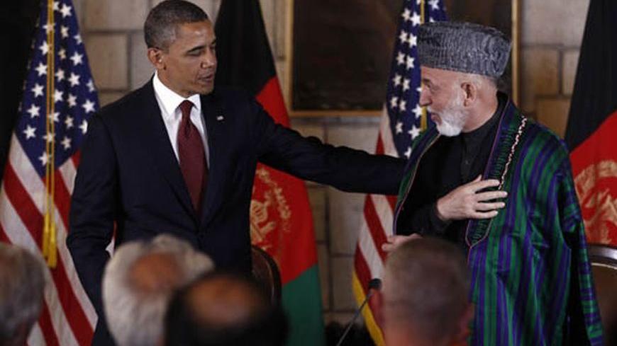 U.S. President Barack Obama puts his arm on Afghan President Hamid Karzai after they signed the Strategic Partnership Agreement at the Presidential Palace in Kabul, May 2, 2012.  The deal insures American military and financial support for the Afghan people for at least a decade beyond 2014, the deadline for most foreign combat forces to withdraw.    REUTERS/Kevin Lamarque (AFGHANISTAN - Tags: POLITICS)