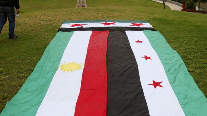 A Syrian Kurd walks past giant Kurdish (L) and Syrian opposition flags ahead of a sit-in in front of the United Nations headquarters in Beirut, in solidarity with anti-government protesters in Syria, April 29, 2012. REUTERS/Cynthia Karam  (LEBANON - Tags: POLITICS CIVIL UNREST)