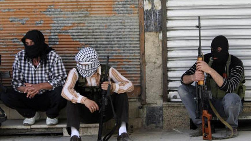 Free Syrian Army members, with covered faces and holding weapons, sit by the side of a street in Qaboun district, Damascus June 11, 2012. REUTERS/Stringer     (SYRIA - Tags: CIVIL UNREST POLITICS MILITARY)