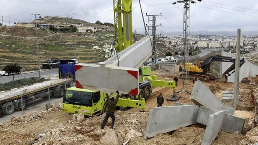 A crane lifts a concrete block for the construction of a section of the controversial Israeli barrier in Shuafat refugee camp in the West Bank near Jerusalem December 5, 2012. Israel moved forward on Wednesday with plans to build some 3,000 settler homes in one of the most sensitive areas of the occupied West Bank, the E1 corridor near Jerusalem, in defiance of international protests. Pisgat Zeev, in an area Israel annexed to Jerusalem after capturing it in the 1967 Middle East war, is seen in the back. REU