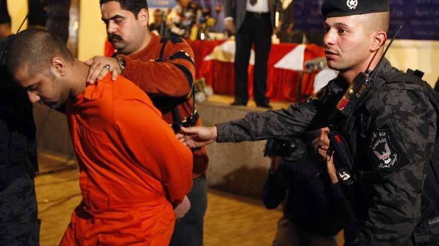 A suspected al-Qaeda militant is taken away by Iraqi police after a presentation to the media at the Interior Ministry in Baghdad November 21, 2011. A total of 22 suspected militants were presented to the media on Monday as they await their trial, according to the police. REUTERS/Saad Shalash (IRAQ - Tags: POLITICS CIVIL UNREST CRIME LAW)