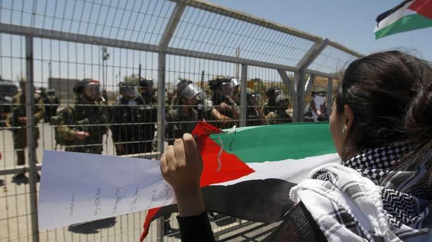 A Palestinian protester holds a flag in front of Israeli soldiers and border police during a protest outside Ofer prison near the West Bank city of Ramallah, marking the anniversary of the 1967 Middle East War, June 5, 2012. REUTERS/Mohamad Torokman (WEST BANK - Tags: POLITICS CIVIL UNREST)