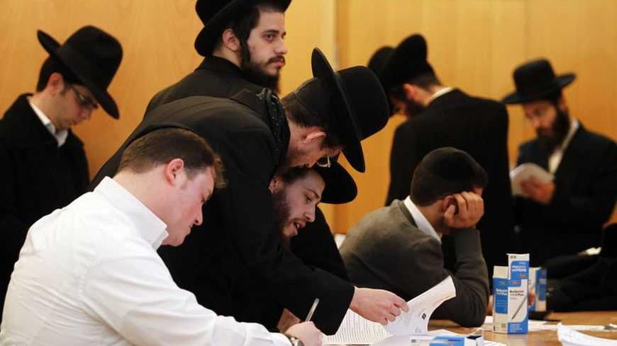 Ultra-Orthodox Jewish men sign documents at the offices of Israel's Administration for National Civil Service in Jerusalem January 6, 2013. For the first time since the August 1 expiration of the so-called Tal Law that exempted ultra-Orthodox seminary students from military conscription, dozens of scholars signed up on Sunday for alternative civilian service which, upon completion, will entitle them to avoid the draft. Some 1,300 seminary students are slated to join the program by August 2013, or until Isra