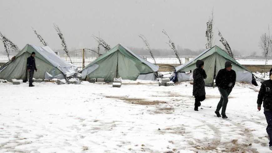 Syrian refugees stand in snow outside their tents during a winter storm in al-Marj, in the Bekaa valley January 9, 2013. The worst winter storm in two decades has hit the eastern Mediterranean this week, bringing destruction and death to Syria and its neighbours who are already dealing with a refugee crisis from the country's civil war. REUTERS/Afif Diab (LEBANON - Tags: ENVIRONMENT DISASTER)