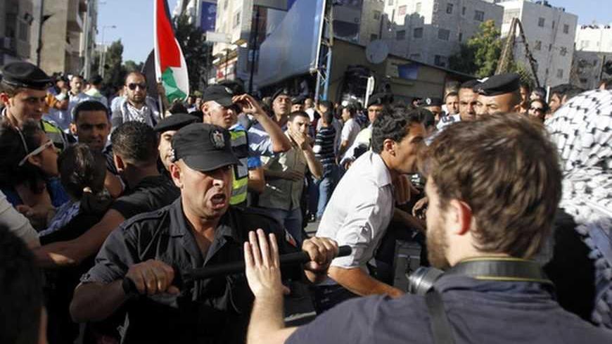 A member of the Palestinian security forces scuffles with a journalist in the West Bank city of Ramallah July 1, 2012, during a protest by Palestinians against a meeting between President Mahmoud Abbas and Israeli Vice Premier Shaul Mofaz that had been put off. Abbas has postponed the controversial meeting with Mofaz that had been scheduled for Sunday, Palestinian officials said on Saturday. REUTERS/Mohamad Torokman (WEST BANK - Tags: POLITICS CIVIL UNREST) - RTR34GAN