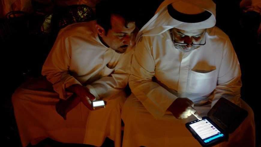 Kuwaiti citizen Raken Subaiya checks his Twitter feed on his phone as Yousef al Anazi looks on during a sit-in protest in front of the Justice Palace in Kuwait City October 19, 2012. The protest is against the detention of three former lawmakers and four citizens, including the son of the former Speaker of Parliament and prominent opposition politician Ahmed al-Saadoun. REUTERS/Stephanie Mcgehee (KUWAIT - Tags: POLITICS CIVIL UNREST)