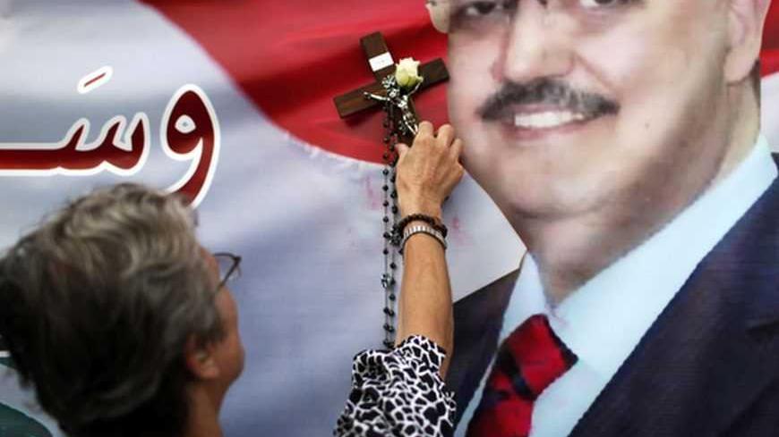 A Christian woman uses a cross and a rosary to bless a poster with an image of senior intelligence official Wissam al-Hassan during a protest against his killing, at Martyrs' square in downtown Beirut October 20, 2012. Lebanese Prime Minister Najib Mikati said on Saturday he had been asked by the president to stay in his post as fear and anger over the assassination of a senior intelligence chief opposed to the Syrian leadership gripped the country. REUTERS/Ahmed Jadallah    (LEBANON - Tags: POLITICS CIVIL 