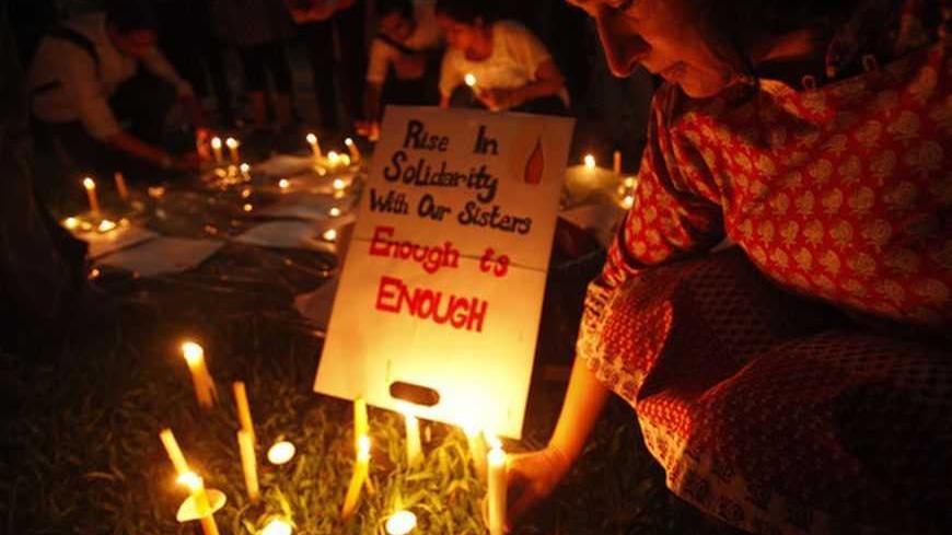 A participant leaves a candle next to a sign during a candlelight vigil for the Indian rape victim, who passed away last Friday, in Singapore January 2, 2013. The death of the 23-year-old woman, who has not been named, prompted street protests across India, international outrage and promises from the government of tougher punishments for offenders. About 150 people took part in the vigil in Singapore. REUTERS/Edgar Su (SINGAPORE - Tags: OBITUARY SOCIETY CIVIL UNREST)