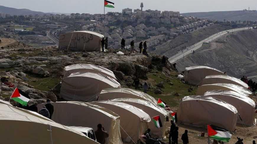 Palestinians, together with Israeli and foreign activists, stand near newly-erected tents in an area known as E1, near Jerusalem January 12, 2013. Palestinians from villages in the occupied West Bank near Jerusalem pitched tents on Friday on the land Israel has earmarked for a new urban settlement, looking to preserve the area for an independent Palestinian state.  REUTER/Baz Ratner (WEST BANK - Tags: POLITICS CIVIL UNREST BUSINESS CONSTRUCTION)