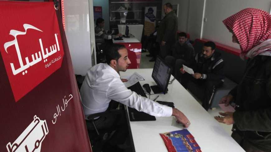 An Iraqi employee sells Asiacell simcards for cell phones in the Asiacell company headquarters in Baghdad, December 30, 2012. Investors will get a chance to buy into the country's oil-fuelled economic boom this month as Asiacell seeks to raise at least $1.35 billion by floating 25 percent of its share capital on the Baghdad stock market. Picture taken December 30, 2012. To match story IRAQ-TELECOMS/ REUTERS/Saad Shalash  (IRAQ - Tags: BUSINESS TELECOMS) - RTR3C1RM