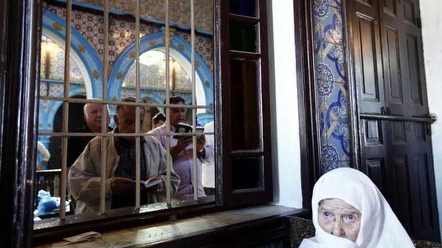 A woman listens as men read the Torah on the first day of a pilgrimage at the Ghriba synagogue in Djerba May 9, 2012. The Ghriba synagogue in Djerba, home to most of Tunisia's Jews, is built on the site of a Jewish temple that is believed to date back almost 1,900 years and attracts pilgrims each year. REUTERS/Anis Mili (TUNISIA - Tags: RELIGION TRAVEL POLITICS) - RTR31U3J