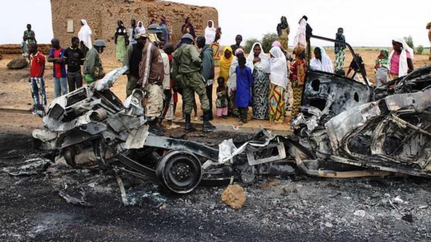 Residents look at the remains of vehicles which they said belonged to radical Islamist group MUJAO, after they were hit by French air strikes in the town of Gao January 27, 2013. Picture taken January 27, 2013.   REUTERS/Adama Diarra (MALI - Tags: CIVIL UNREST MILITARY POLITICS TPX IMAGES OF THE DAY) - RTR3D6AR