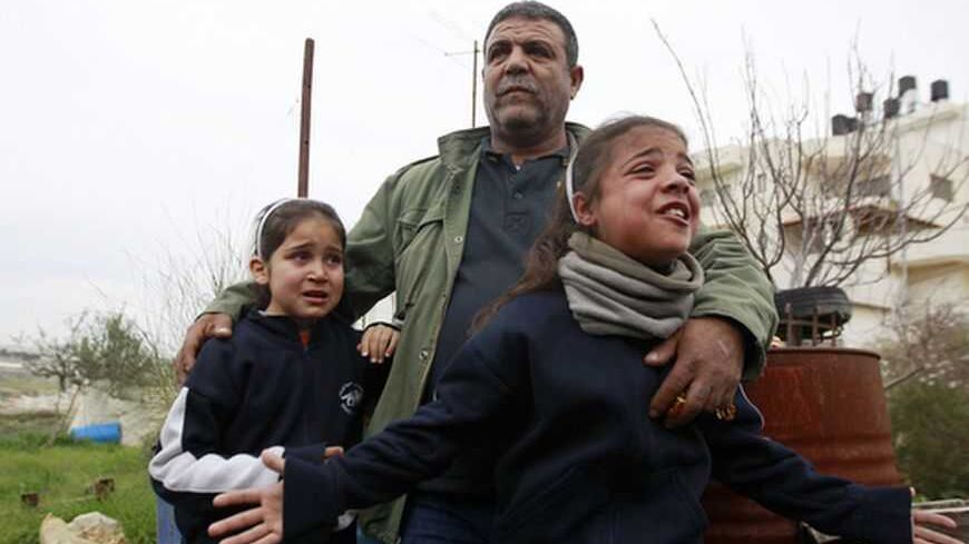 Dina (R), a nine-year-old Palestinian girl, cries as her father Saleh Kostero puts his arms around her and her cousin Halla (L) during the demolition of their house in the East Jerusalem neighbourhood of Beit Hanina February 5, 2013. A statement from the Jerusalem Municipality said there was a court order for the demolition of the house, which was built without a permit in an open landscape area where construction is forbidden. REUTERS/Ammar Awad (JERUSALEM - Tags: POLITICS CIVIL UNREST BUSINESS CONSTRUCTIO