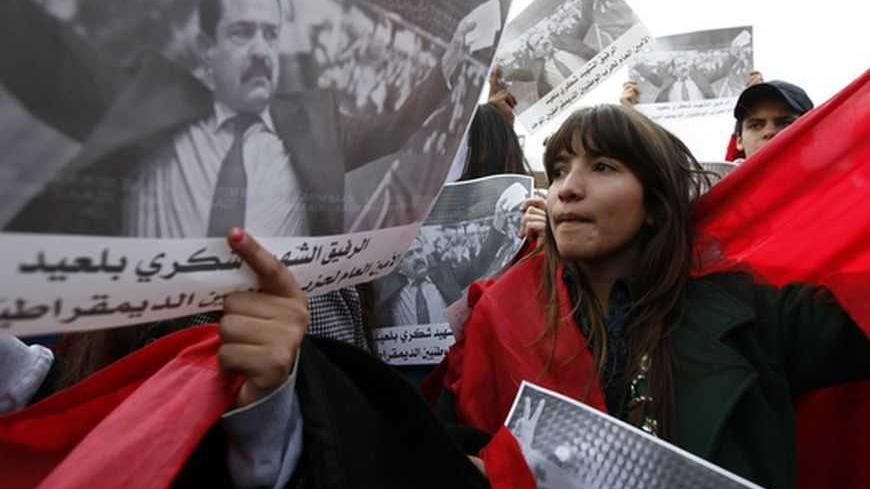 A woman stands next to a poster of assassinated leftist politician Chokri Belaid during a demonstration, calling for Prime Minister Hamadi Jebali and his cabinet to step down, at the National Constituent Assembly in Tunis, February 11, 2013. A party led by interim President Moncef Marzouki said on Monday it had "frozen" its withdrawal from Tunisia's coalition government while talks continue on a political crisis sharpened by the killing of an opposition politician. Belaid's killing - Tunisia's first such po