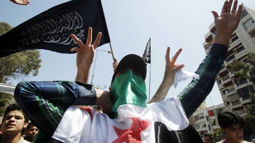 A protester covers his face with the Syrian opposition flag as he gestures and shout slogans, during a demonstration, organised by the Future Movement against Syria's President Bashar al-Assad, after Friday prayers in Beirut, April 27, 2012.   REUTERS/Sharif Karim (LEBANON - Tags: POLITICS CIVIL UNREST) - RTR31AEX