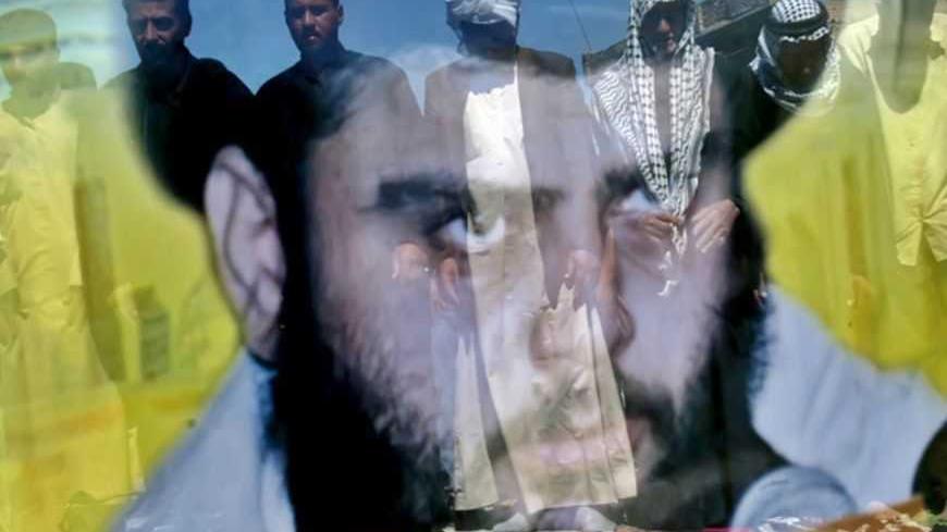 Iraqi Muslim worshippers, reflected on a portrait of the Shi'ite cleric Muqtada al-Sadr, perform Friday Prayers outside al-Sadr's office in eastern Baghdad March 25, 2005. REUTERS/Ali Jasim  HH/CCK - RTR61YO