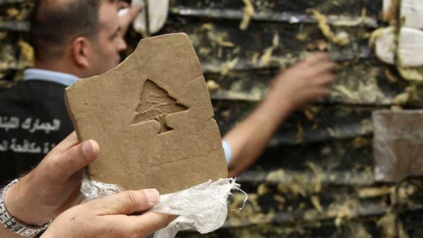 A Lebanese customs employee displays a packet of confiscated hashish stamped with a Lebanese cedar in Beirut May 27, 2009. Lebanese Internal Security forces and Lebanese Customs anti-drugs trafficking division seized a total of 85 kg (187 lbs) of hashish hidden in a refrigerated container that was supposed to be smuggled into the Netherlands. REUTERS/Mohamed Azakir   (LEBANON SOCIETY CRIME LAW) - RTXOFL7