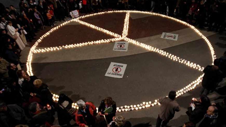 Members from peace groups gather around a peace sign formed by lighted candles, remembering the tenth anniversary of the Iraq War at Plaza de Catalunya, central Barcelona March 20, 2013.         REUTERS/Gustau Nacarino  (SPAIN - Tags: CIVIL UNREST) - RTR3F8PV