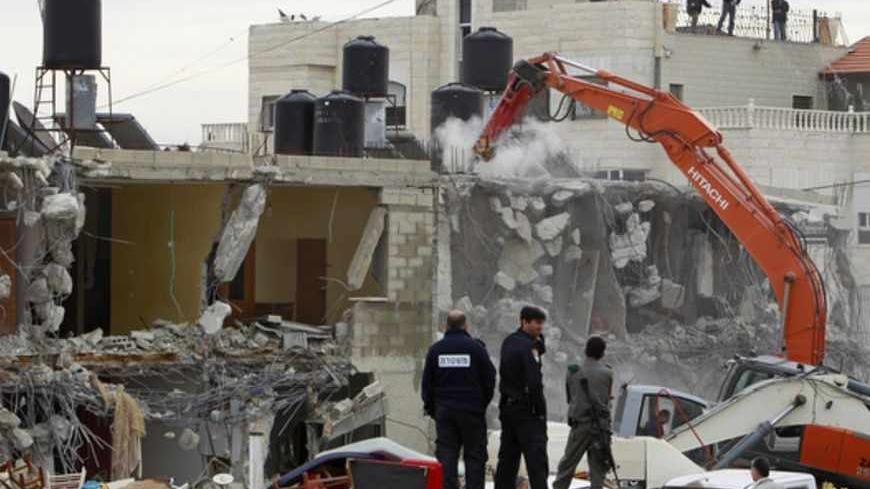Israeli police officers look as an excavator demolishes a house in the East Jerusalem neighbourhood of Beit Hanina February 5, 2013. A statement from the Jerusalem Municipality said there was a court order for the demolition of the house, which was built without a permit in an open landscape area where construction is forbidden. REUTERS/Ammar Awad (JERUSALEM - Tags: POLITICS CIVIL UNREST BUSINESS CONSTRUCTION) - RTR3DDS4