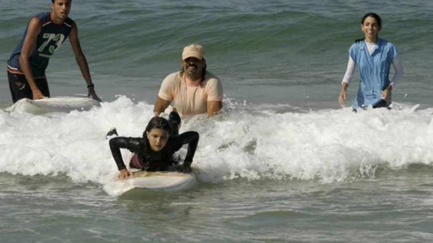 Rajab Abu Ghanim (rear C) teaches his daughter, Palestinian girl Shorouq Abu Ghanem, to surf in the Mediterranean Sea off the coast of Gaza City November 5, 2010. Away from Gaza's troubled reality and beyond its polluted shore, Shorouq and Sabah Abu Ghanem surf in a world of their own. The two girls, 13 and 12, learnt how to swim at the age of three at the hand of their lifeguard father. They can swim up to 10 km (6 miles), dive to seven meters (25 feet) and surf on plastic boards that they hope one day to 