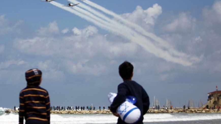 Children watch Israeli Air Force planes fly over the Mediterranean Sea from a Tel Aviv beach, during an aerial show as part of celebrations for Israel's Independence Day, marking the 65th anniversary of the creation of the state, April 16, 2013. REUTERS/Amir Cohen (ISRAEL - Tags: ANNIVERSARY ENVIRONMENT TRANSPORT MILITARY) - RTXYNTO